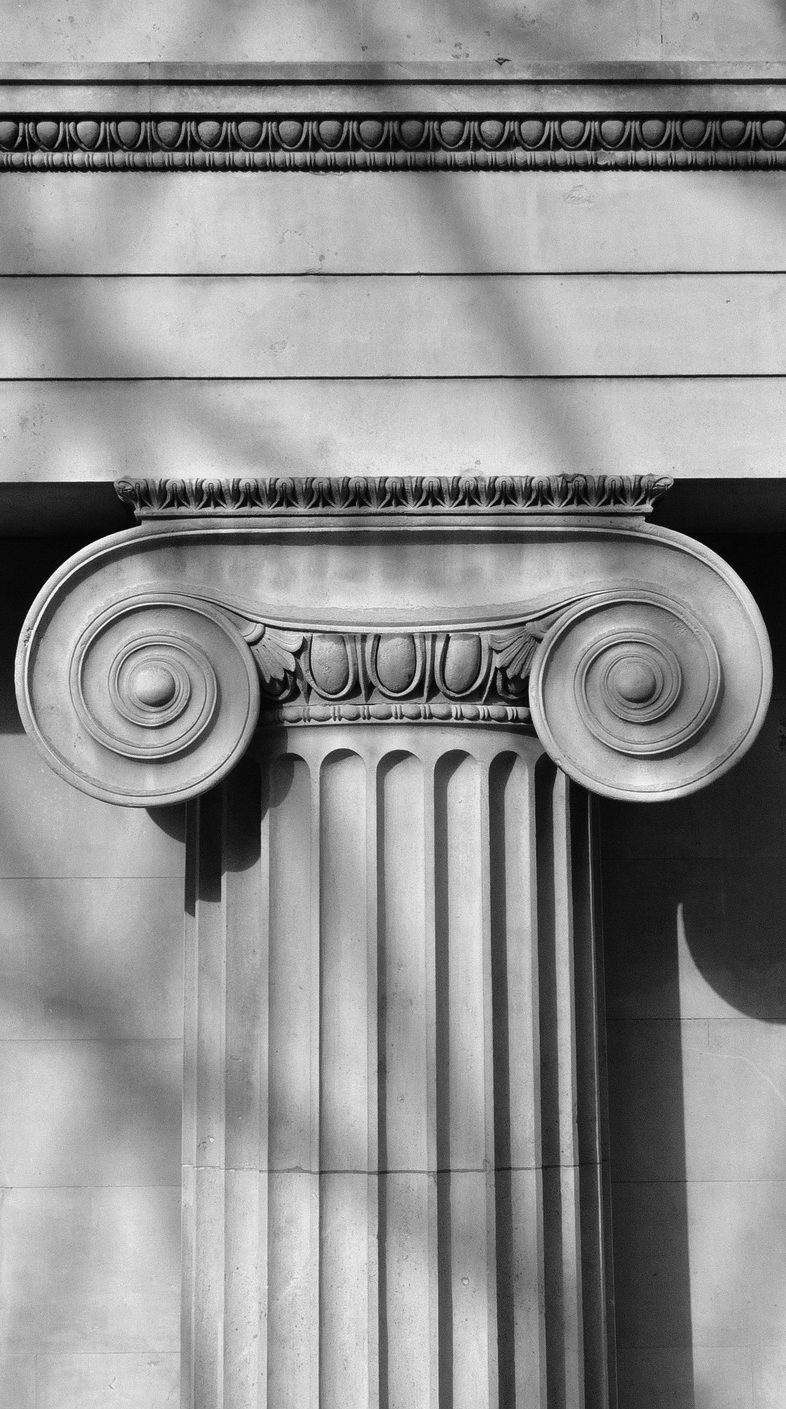 Ionic capital with shadow of modern roof frame.